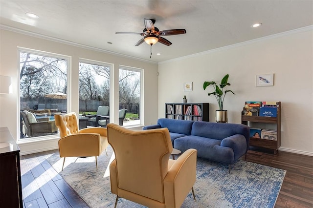 living area with a ceiling fan, crown molding, wood finished floors, and baseboards