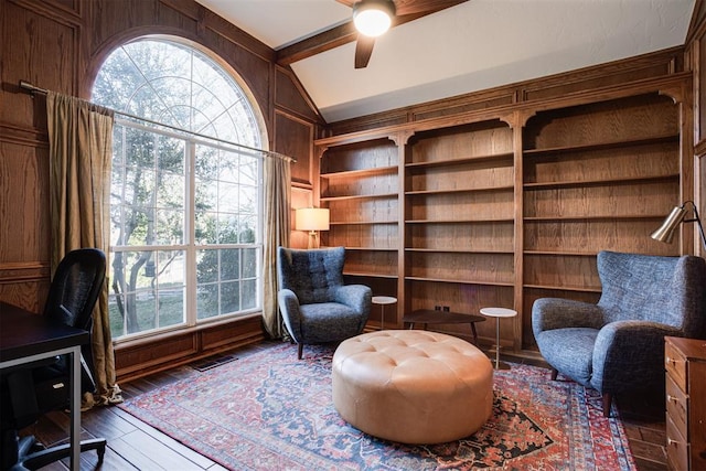 interior space featuring wood walls, wood finished floors, a ceiling fan, and vaulted ceiling