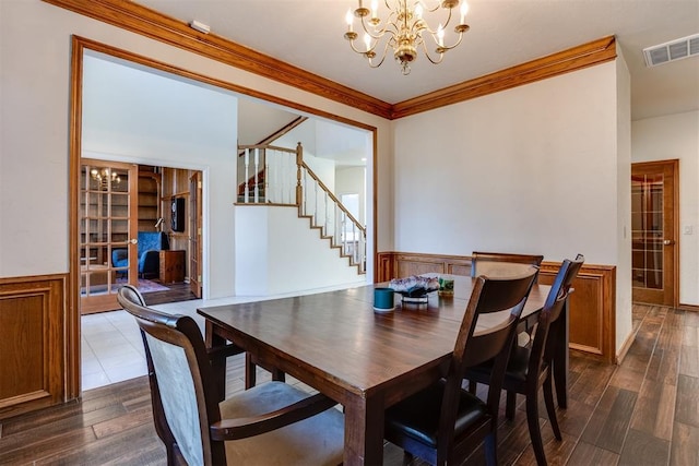 dining space with visible vents, crown molding, dark wood finished floors, a wainscoted wall, and a notable chandelier