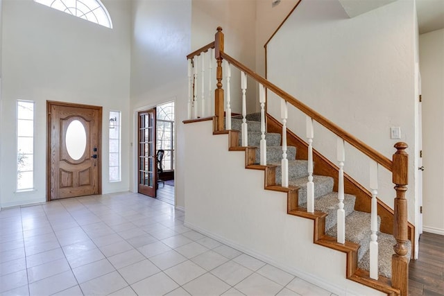 foyer entrance with a wealth of natural light, baseboards, stairs, and a towering ceiling