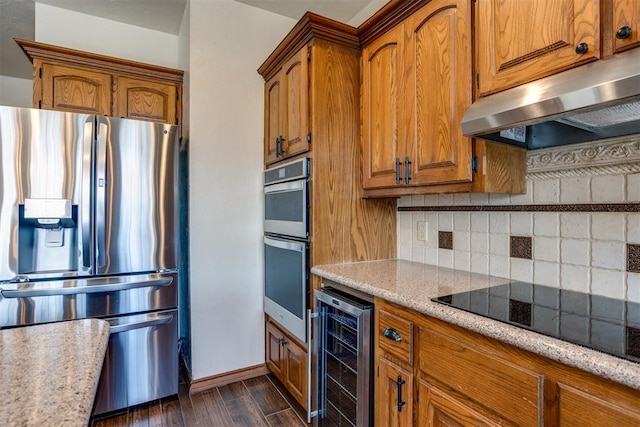 kitchen with dark wood-style floors, brown cabinetry, beverage cooler, under cabinet range hood, and appliances with stainless steel finishes