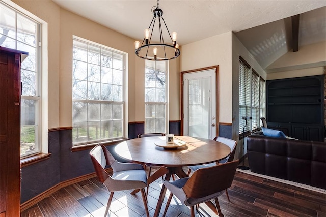 dining space featuring a notable chandelier, vaulted ceiling with beams, wainscoting, and wood tiled floor