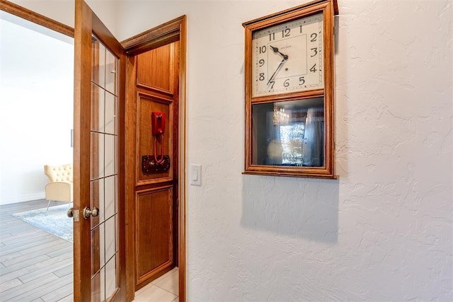 hall featuring light wood-style floors and a textured wall