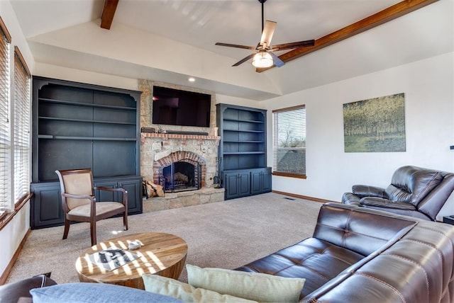 carpeted living room featuring built in shelves, baseboards, ceiling fan, lofted ceiling with beams, and a fireplace