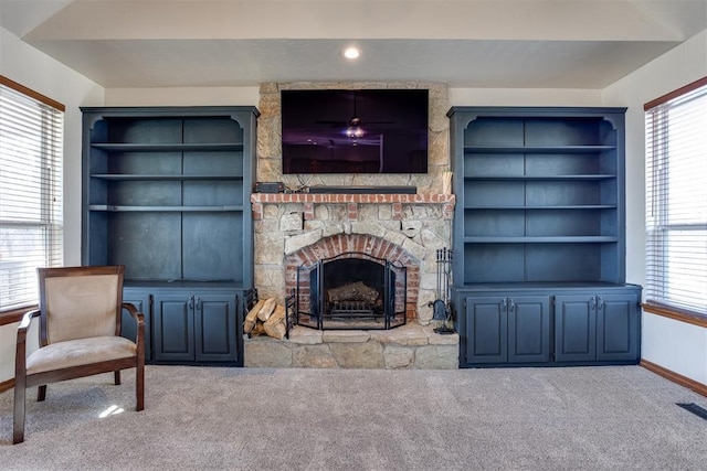 carpeted living area featuring built in shelves, a fireplace, visible vents, and baseboards