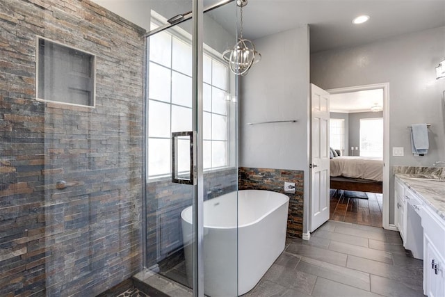 ensuite bathroom featuring vanity, connected bathroom, a freestanding tub, a shower stall, and a chandelier