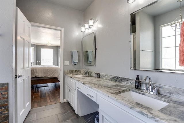 ensuite bathroom featuring a wealth of natural light, double vanity, and a sink