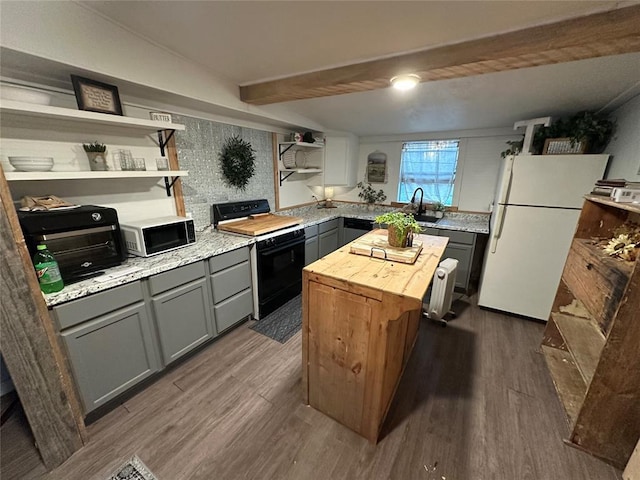 kitchen with gray cabinetry, open shelves, freestanding refrigerator, wooden counters, and black range oven