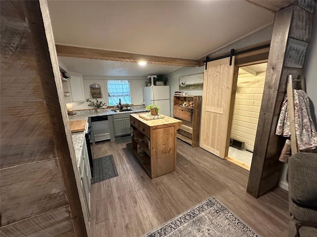 kitchen featuring wooden counters, open shelves, freestanding refrigerator, a sink, and a barn door