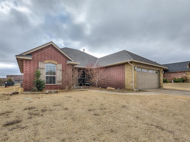 ranch-style house with driveway, fence, an attached garage, a shingled roof, and brick siding