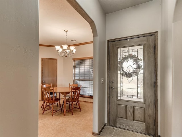 entrance foyer with ornamental molding, a notable chandelier, arched walkways, and plenty of natural light