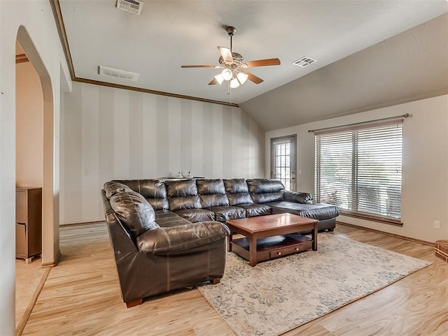 living room with light wood finished floors, visible vents, wallpapered walls, arched walkways, and a ceiling fan