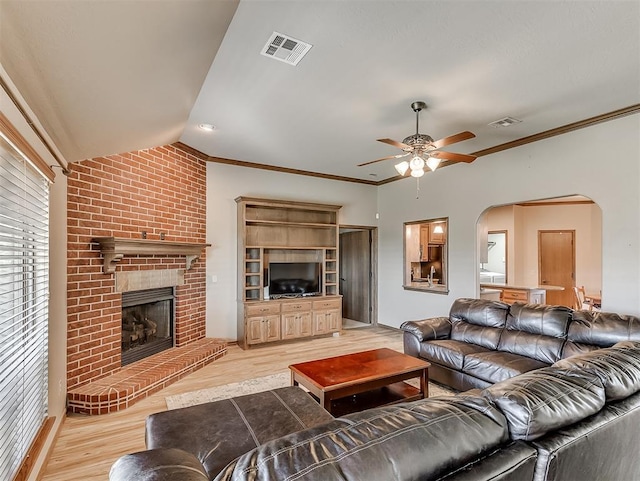 living area featuring visible vents, a ceiling fan, arched walkways, crown molding, and light wood finished floors