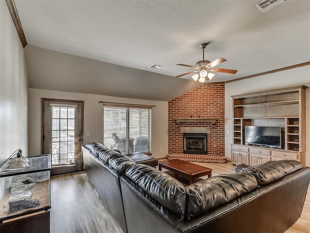 living room featuring light wood-style floors, lofted ceiling, a ceiling fan, and visible vents