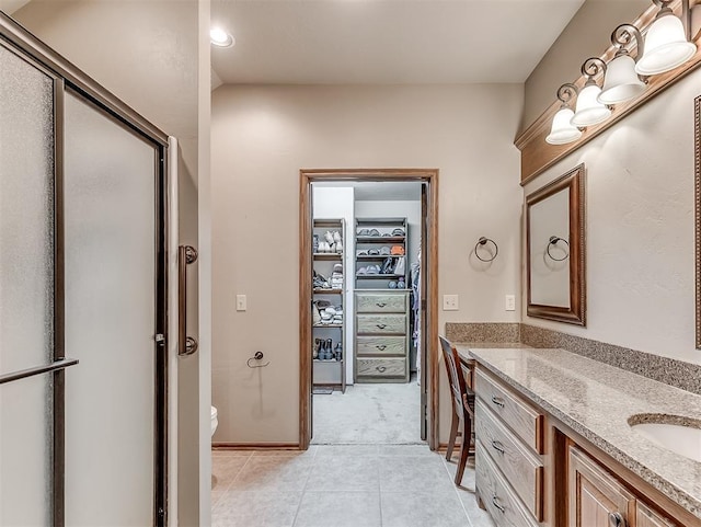 full bath with vanity, a shower with shower door, tile patterned flooring, a walk in closet, and toilet