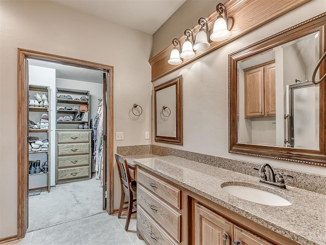 bathroom featuring tile patterned floors, vanity, and a walk in closet