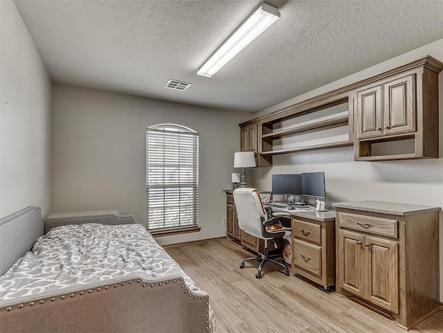 bedroom featuring visible vents, a textured ceiling, and light wood finished floors