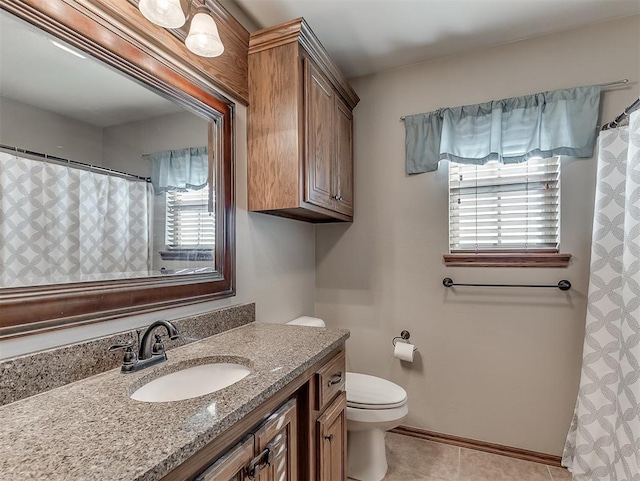 bathroom with tile patterned floors, a healthy amount of sunlight, toilet, and vanity