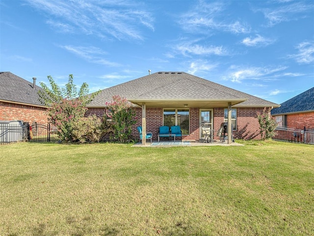 rear view of house featuring a patio area, a lawn, and a shingled roof