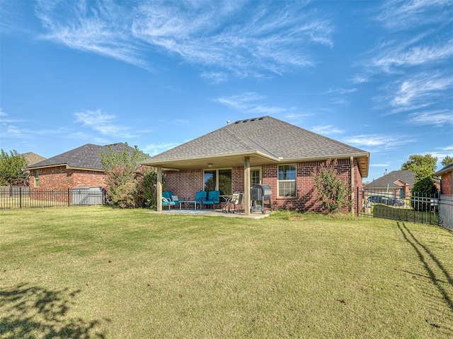 back of house with brick siding, roof with shingles, a fenced backyard, a yard, and a patio