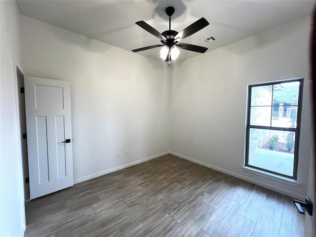 spare room featuring visible vents, ceiling fan, baseboards, and wood finished floors