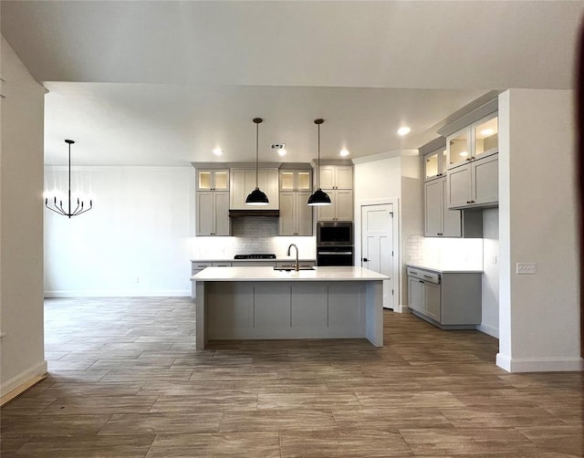 kitchen featuring stainless steel microwave, black oven, backsplash, and a sink