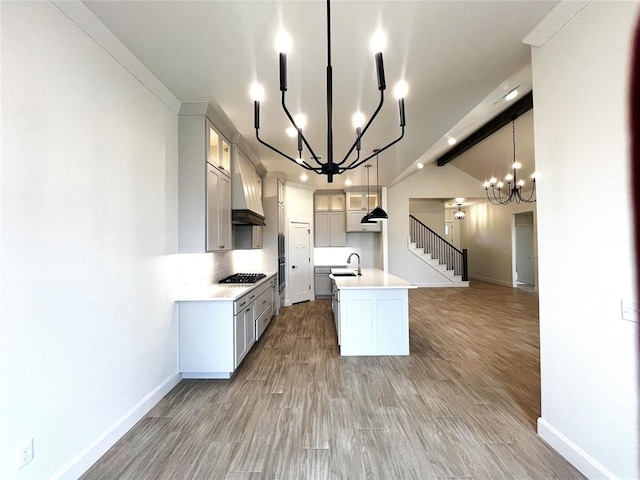 kitchen with light wood finished floors, gas cooktop, light countertops, glass insert cabinets, and baseboards