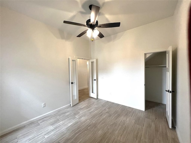 unfurnished bedroom featuring a closet, baseboards, wood finished floors, and a ceiling fan