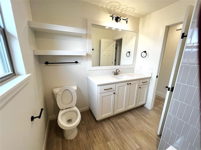 bathroom with baseboards, toilet, wood finished floors, and vanity