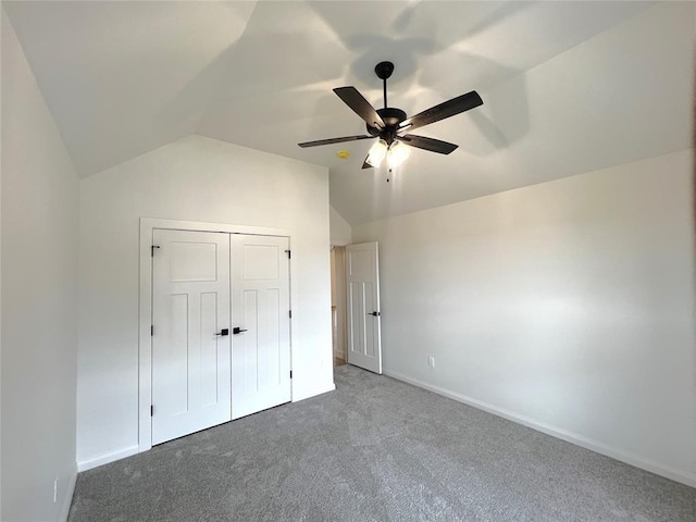 unfurnished bedroom featuring lofted ceiling, a closet, carpet, baseboards, and ceiling fan