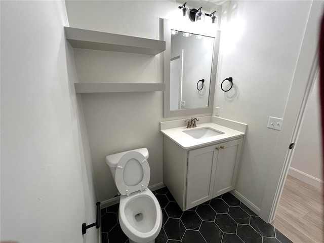 bathroom with baseboards, toilet, and vanity