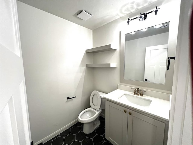 half bath with baseboards, toilet, vanity, and tile patterned flooring