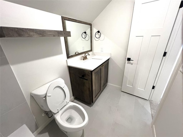 bathroom with toilet, vanity, marble finish floor, and baseboards