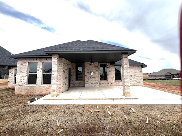 rear view of house with brick siding, ceiling fan, roof with shingles, central AC unit, and a patio