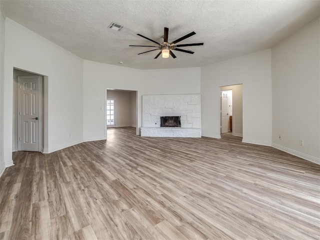 unfurnished living room featuring a ceiling fan, light wood-style floors, a fireplace, and visible vents