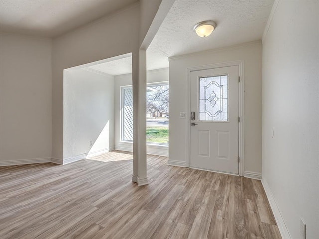 entrance foyer with crown molding, light wood-style flooring, baseboards, and a textured ceiling