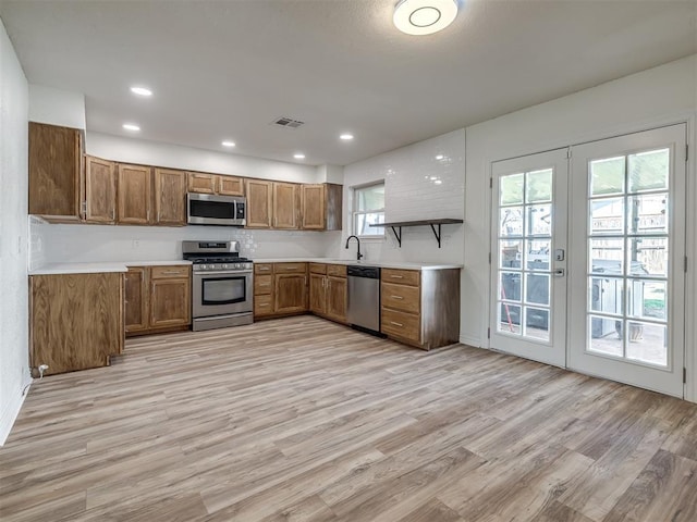 kitchen featuring light wood-type flooring, brown cabinets, visible vents, stainless steel appliances, and french doors