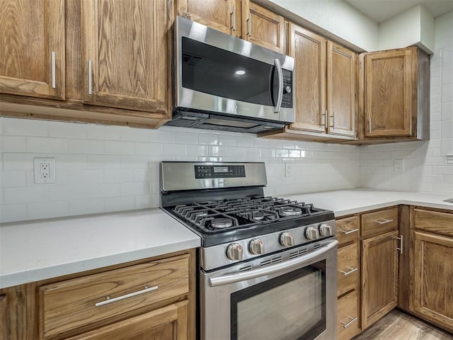 kitchen featuring light countertops, brown cabinetry, tasteful backsplash, and appliances with stainless steel finishes