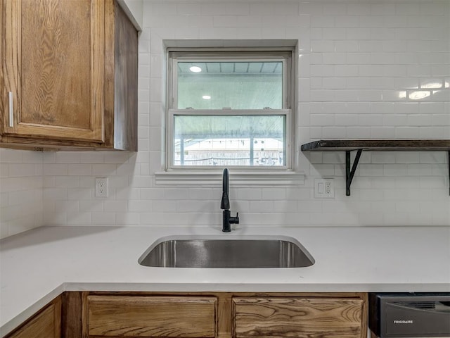 kitchen with a sink, brown cabinetry, and light countertops