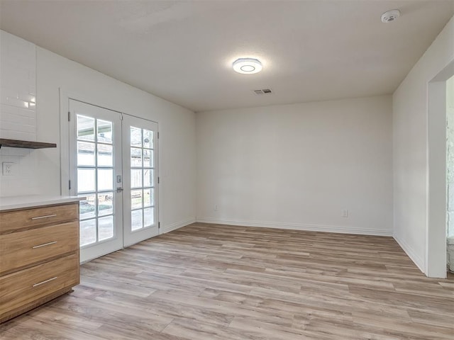 interior space with visible vents, french doors, baseboards, and light wood finished floors