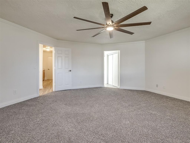 carpeted spare room with crown molding, baseboards, and a textured ceiling