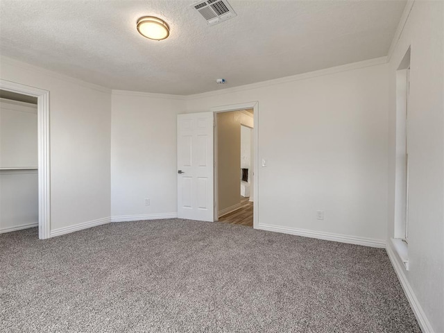 unfurnished bedroom with visible vents, ornamental molding, a textured ceiling, carpet, and baseboards