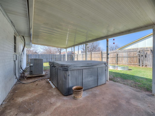 view of patio / terrace with central AC unit, a fenced backyard, and a hot tub