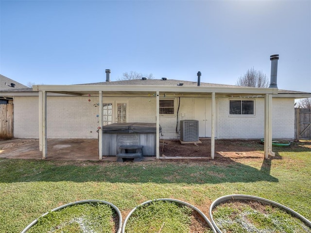 rear view of property with a lawn, a hot tub, central AC, and fence