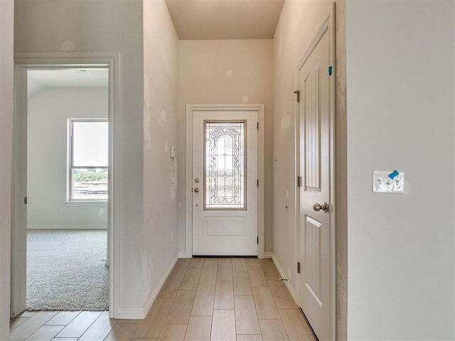 entrance foyer with baseboards and light colored carpet