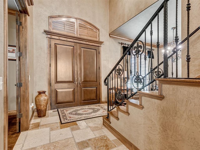 entrance foyer featuring stone tile flooring, stairway, and baseboards