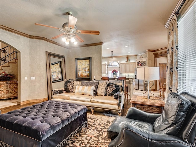 living area featuring ornamental molding, baseboards, arched walkways, and ceiling fan