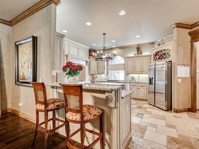 kitchen with baseboards, an inviting chandelier, a peninsula, stainless steel refrigerator with ice dispenser, and crown molding