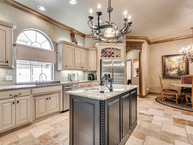 kitchen with stone tile floors, an inviting chandelier, a sink, cream cabinetry, and appliances with stainless steel finishes