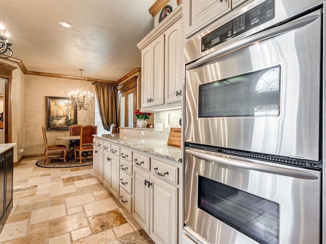 kitchen with crown molding, pendant lighting, stone tile floors, an inviting chandelier, and stainless steel double oven